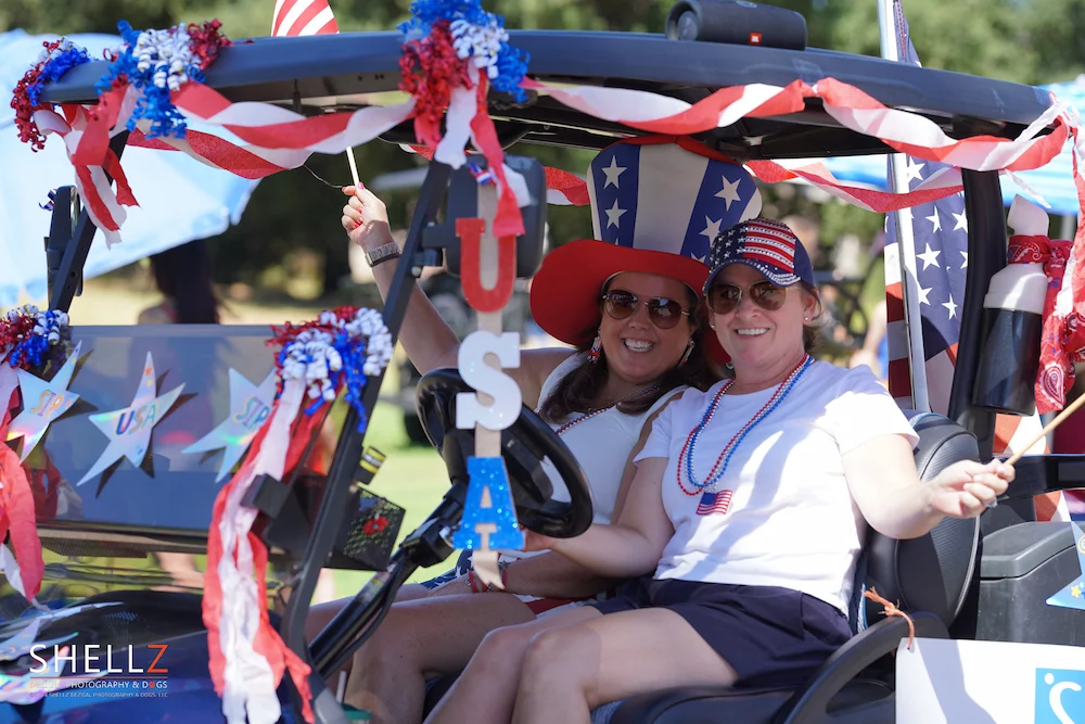 Decorated golf carts lined up for the SDCE 4th of July Golf Cart Parade with the granite mountains in the background